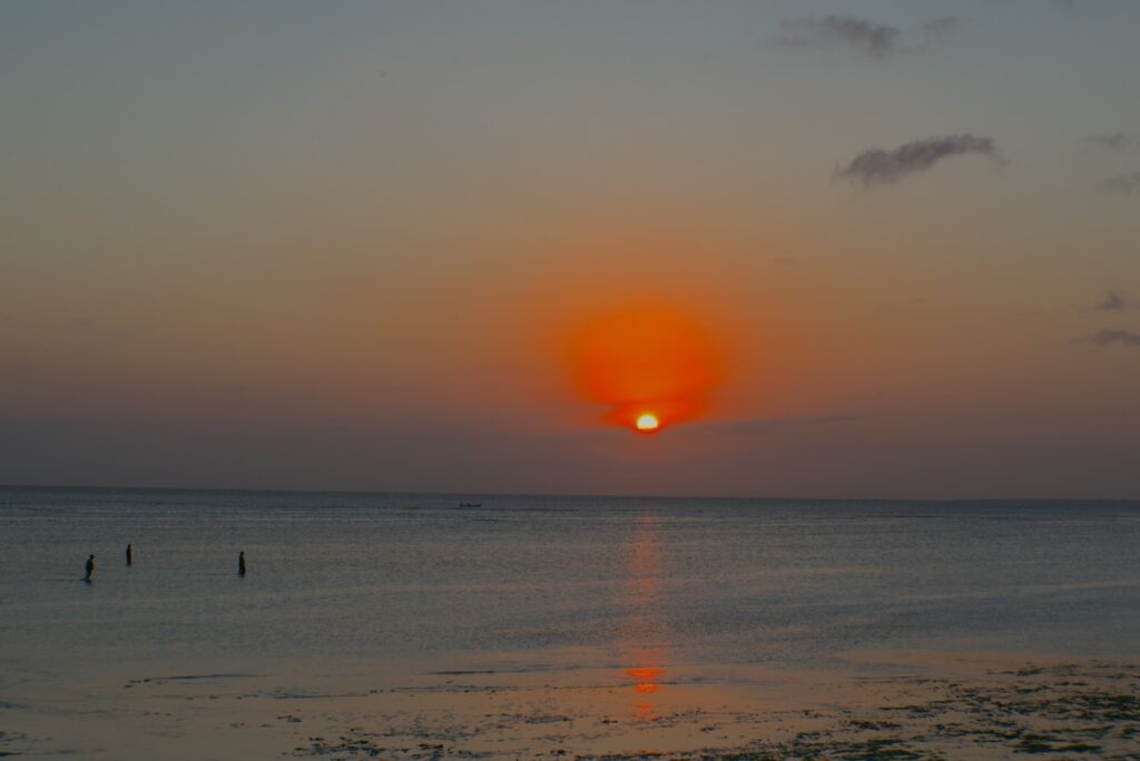 Tramonto infuocato sulla costa Ovest di Zanzibar, mentre le donne locali rientrano dalla pesca